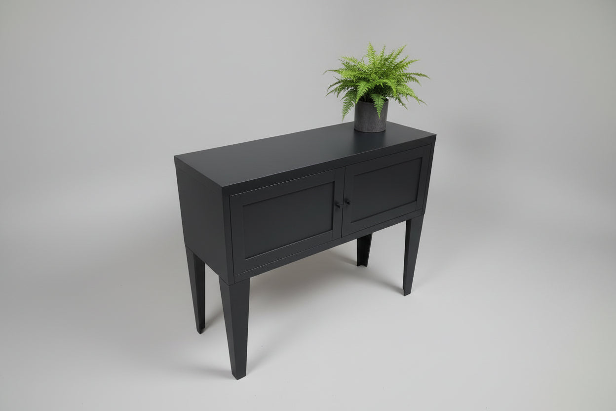 Black metal sideboard with two doors against a light gray wall.