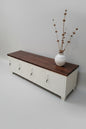 Wooden bench with white storage lockers and decorative items on a light gray floor.