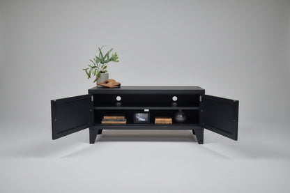 Black metal TV cabinet with door open showing cable holes and shelf