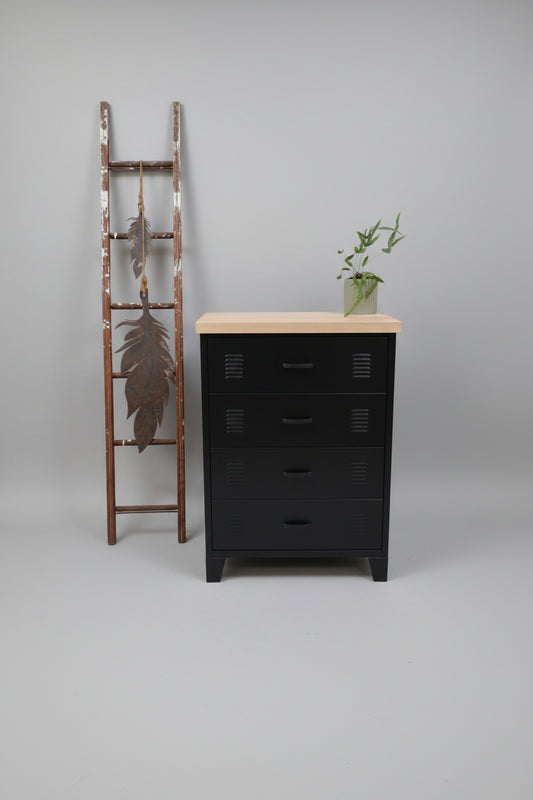 Black metal dresser with Oak wooden top and four drawers next to a decorative ladder with feathers against a light gray wall.