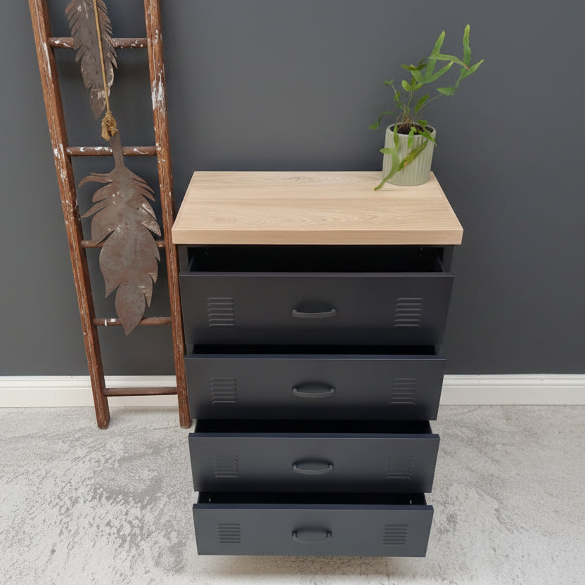 Black metal four drawer cabinet with Oak top against a light gray wall with the drawers open