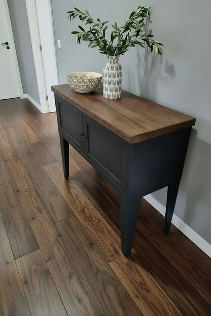 Black metal hall cabinet with storage dark oak top in a hallway of modern house.