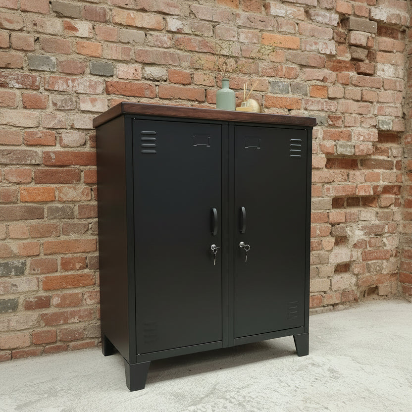 Black metal sideboard style cabinet with dark oak top against a brick wall