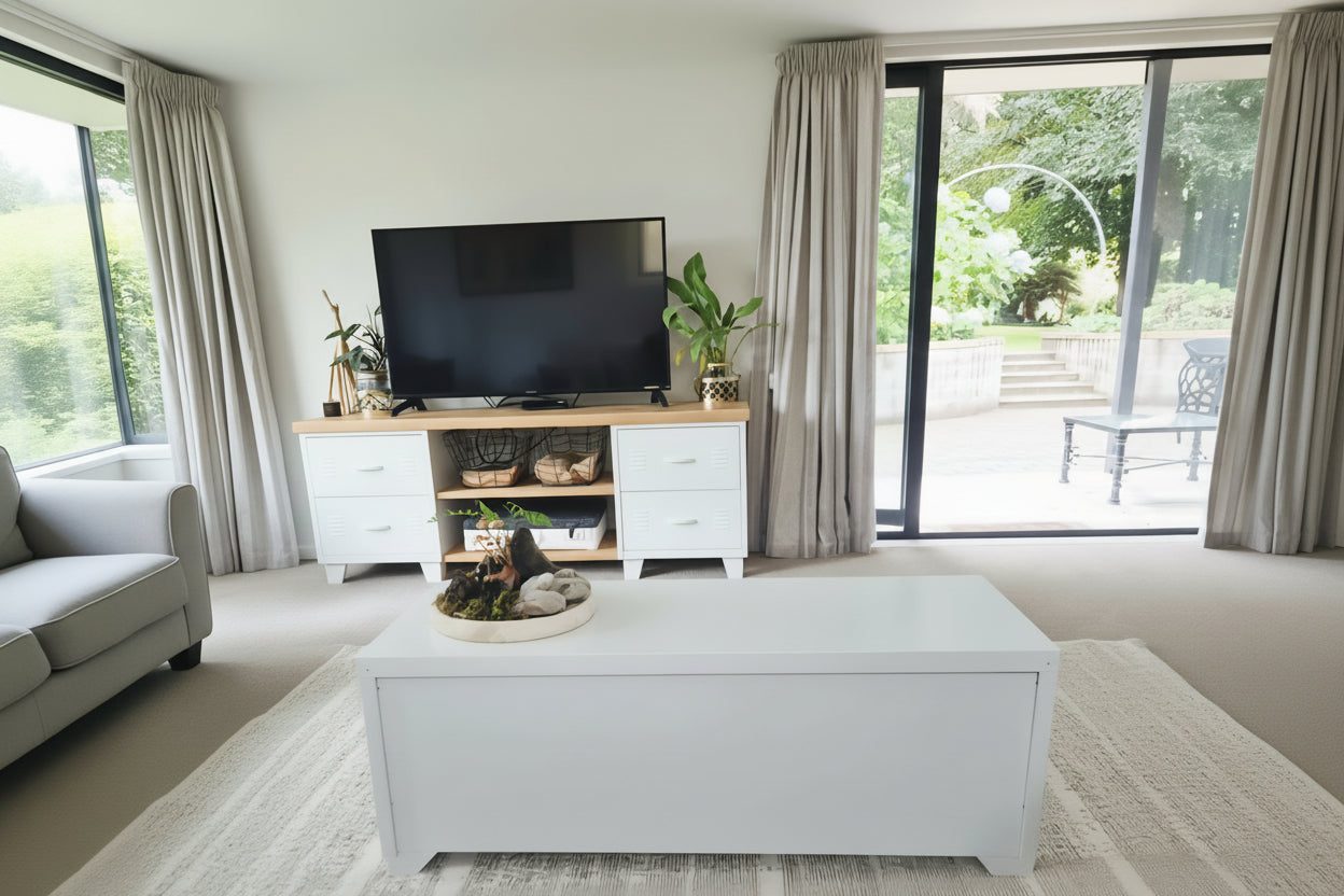 Modern living room with white metal coffee table, showing the back of it, and large windows.