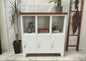 White metal cabinet with wooden Dark Oak top in a room with plants and decorative items.