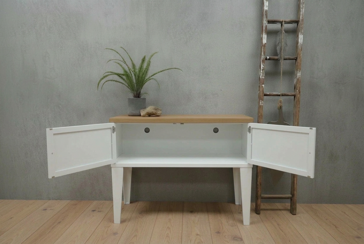 White metal console with open doors against a gray wall with a plant and ladder.