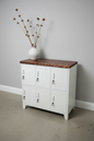 White metal 6 door locker cabinet with Dark oak top against a grey wall