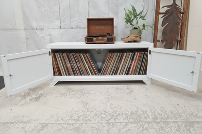 White metal TV cabinet with open doors displaying vinyl records and a vintage record player on a light gray floor.