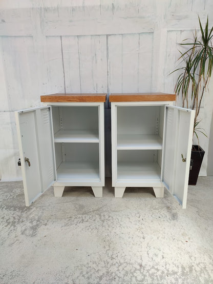 A Pair White metal beside cabinet with Rimu tops open doors. featuring a wooden top against a light gray wall.