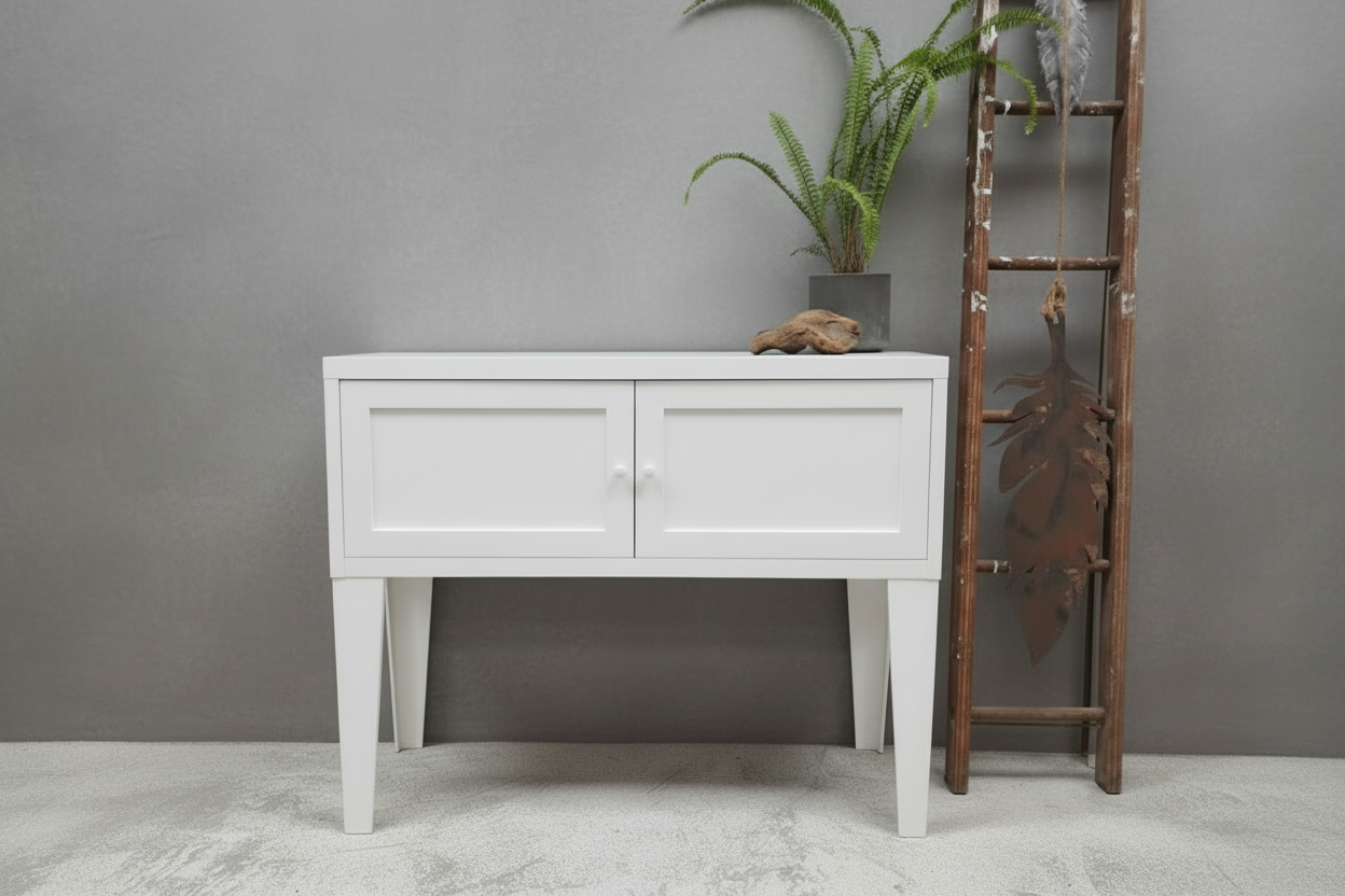 White metal console table against a light gray wall with decorative elements.