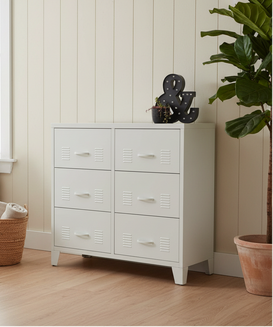 White metal dresser with six drawers against a light wall with a plant on the right.