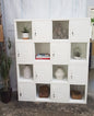 White metal industrial locker-style shelf with decorative items against a white wall.