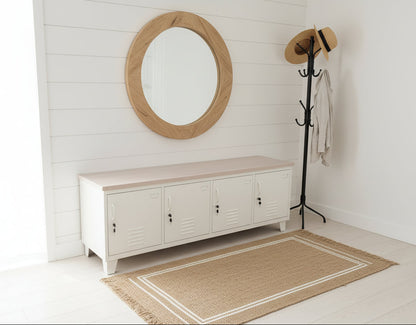 White metal locker cabinet with white washed Oak top with a round mirror and coat rack in a room with white walls and light wood floor.