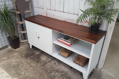 White meatal cabinet with wooden top and open shelves, plants, and books in an outdoor setting.