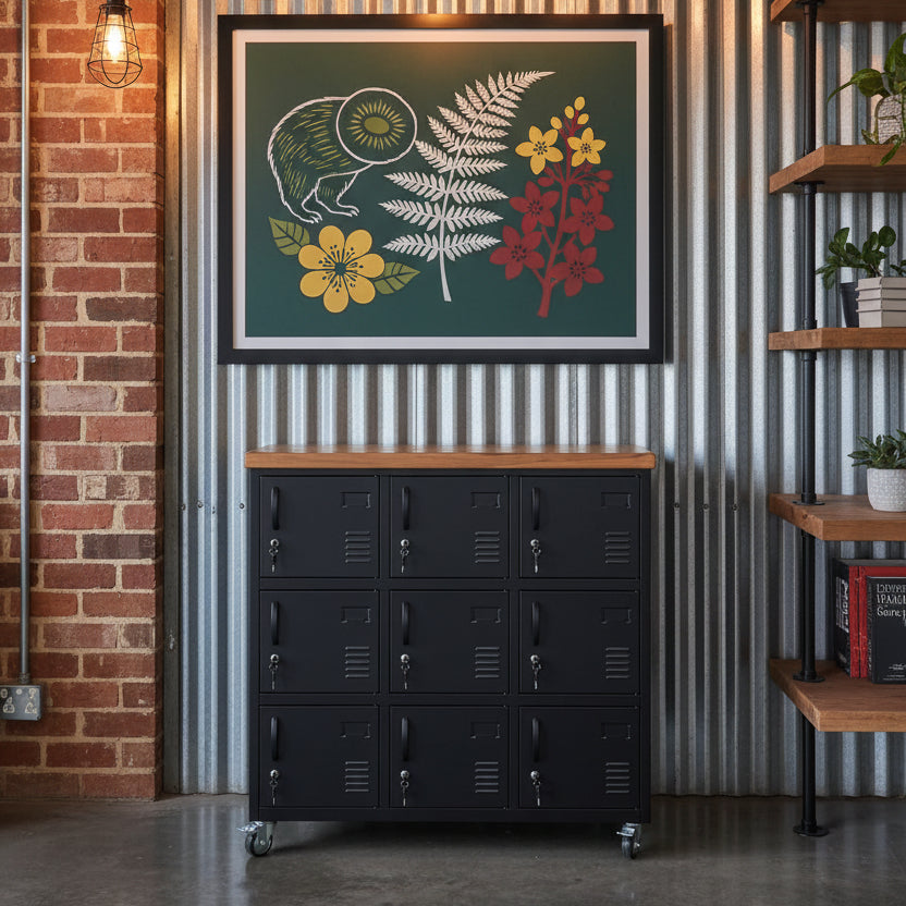 A black metal locker cabinet with nine lockable locker doors and a recycled Rimu top against a tin wall in an industrial office