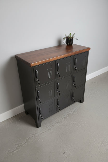 Black metal 9 door locker cabinet with NZ dark stained Rimu top against a grey wall