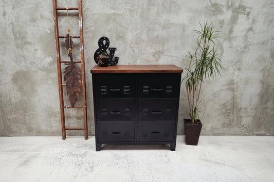 Black metal locker-style dresser with wooden top against a white brick wall.