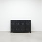 A large black metal locker cabinet with 8 lockable doors stands in a high-ceilinged industrial room.
