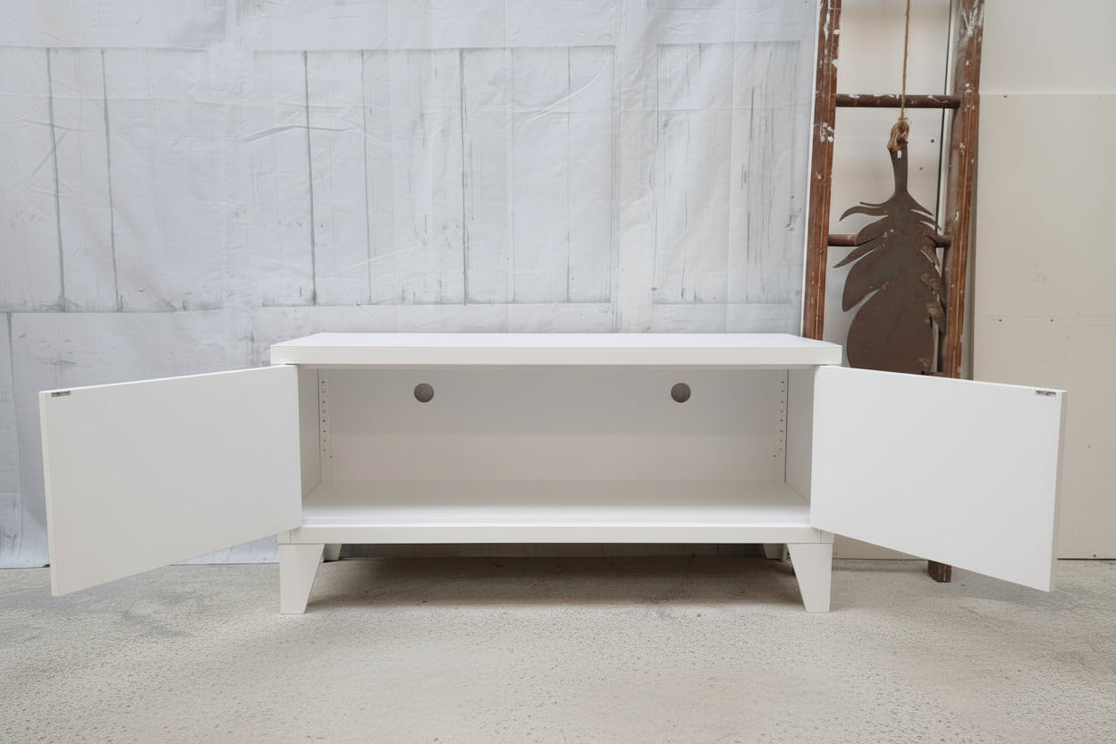 White metal TV cabinet with open doors showing inside with cable holes