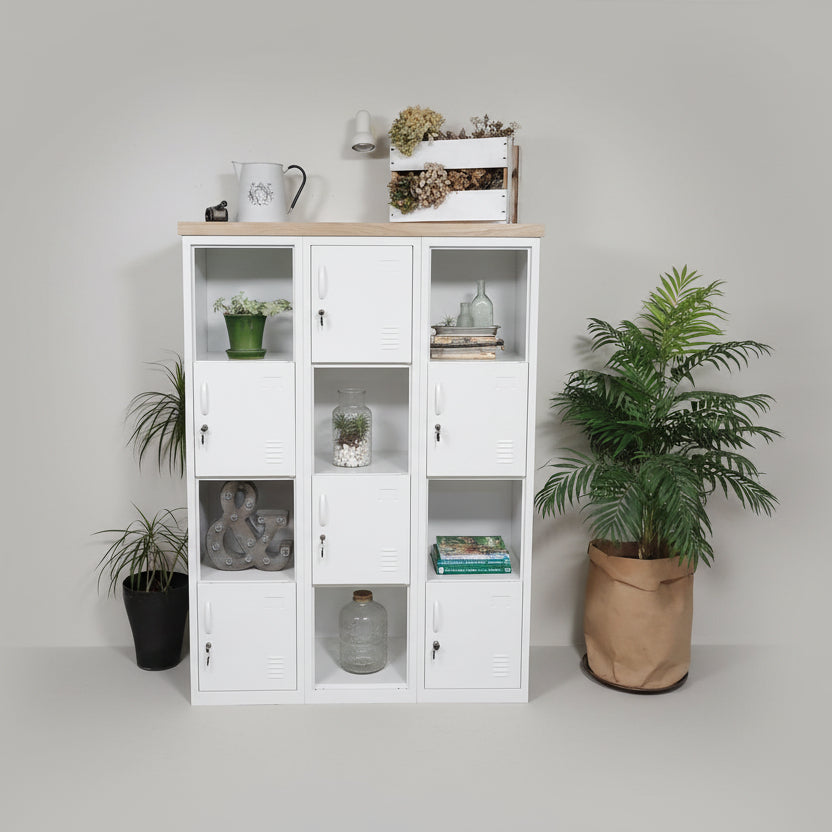 A white metal checkerboard display cabinet with oak top, featuring multiple compartments, some containing plants and decorative items, placed in a room setting with a few items on top, such as a mug and a vase.