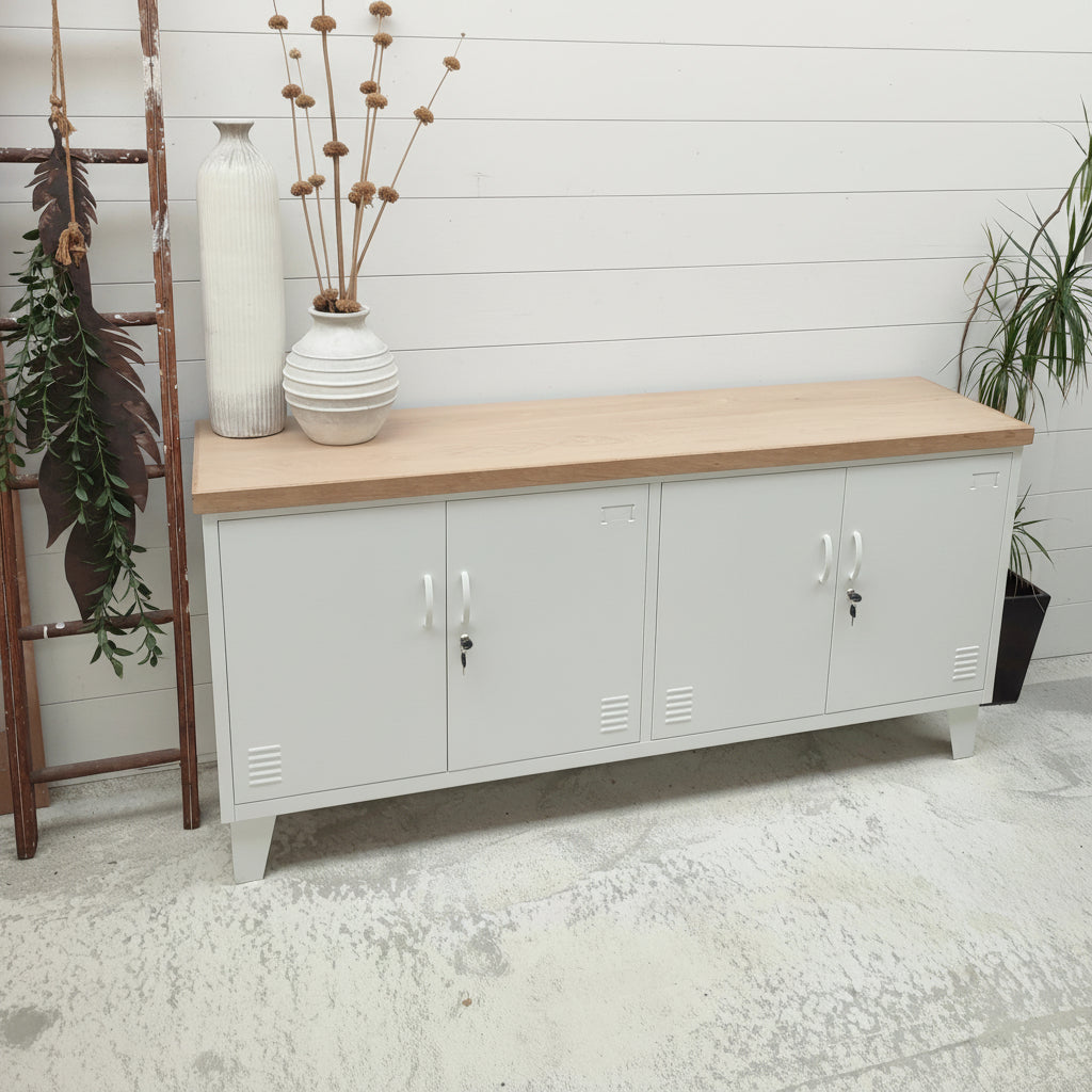 A white metal locker cabinet with an oak top, featuring multiple compartments and lock mechanisms, situated in a room with a white floor and wall.