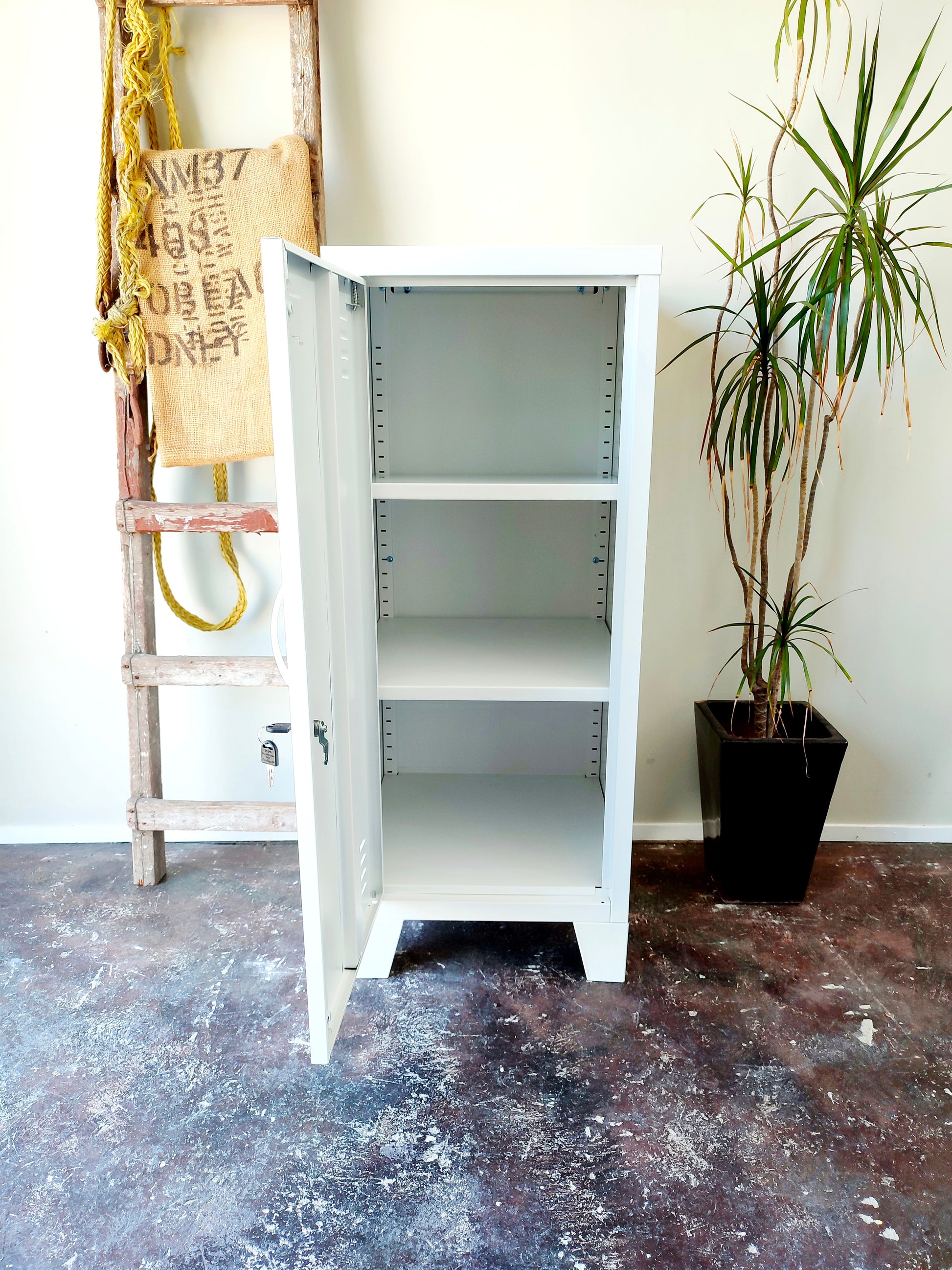 white metal side cabinet with a left hinge door open, showing adjustable shelves