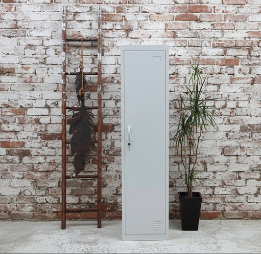 A white slim 1 door metal locker against a brick wall.