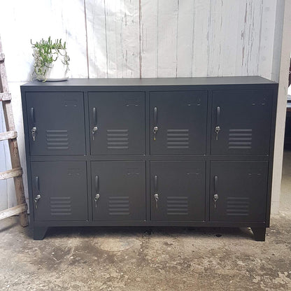 A black metal sideboard locker with eight doors, each with a lock and vent-like design in the center.
