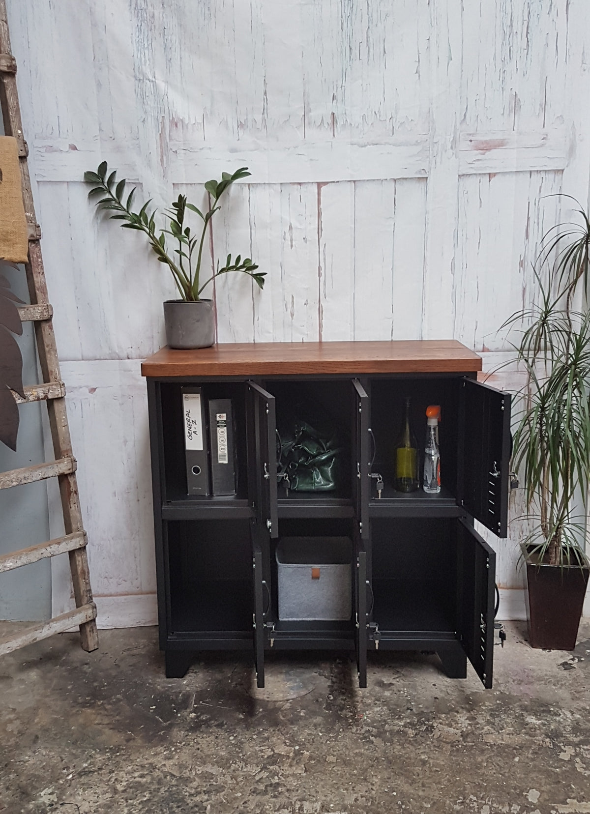 A Black Metal 6-door locker with dark oak top with doors open to show folders, wine bottles and bags inside