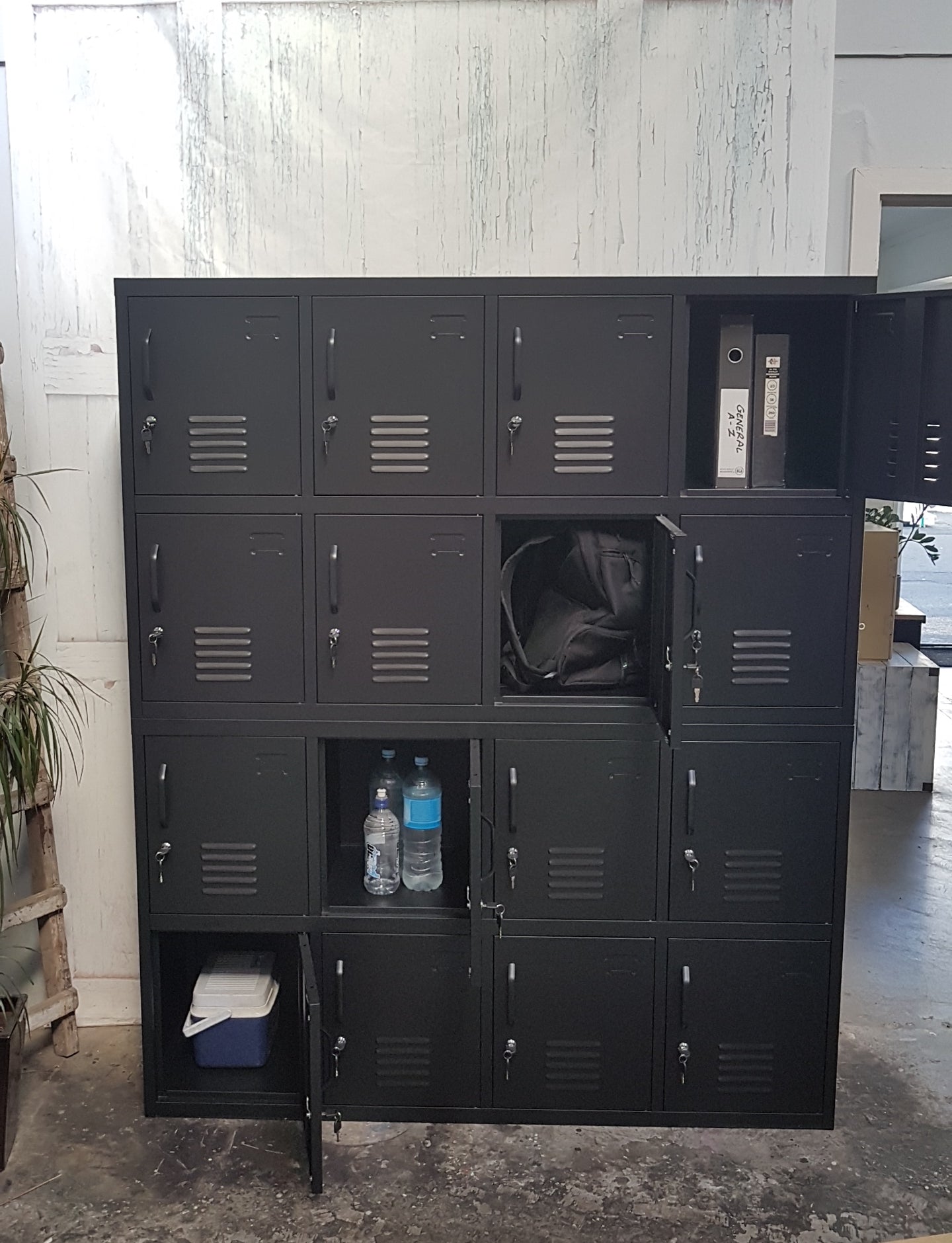 Black metal 16-door staff locker with some doors open to show use