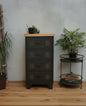 A black metal 4-drawer unit with an oak top, positioned in a room with various decor.