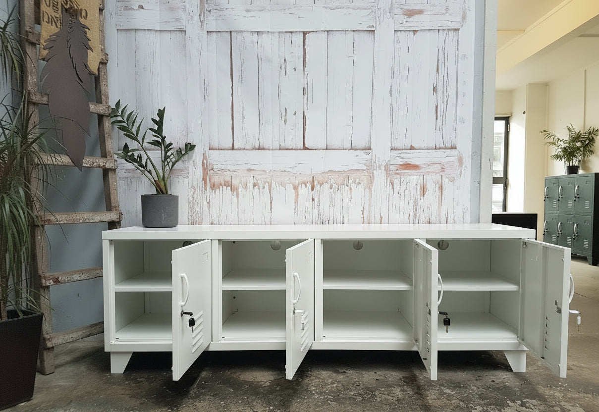 Large White metal entertainment cabinet with open doors showing cable holes and shelves inside in a room with wooden walls and plants.