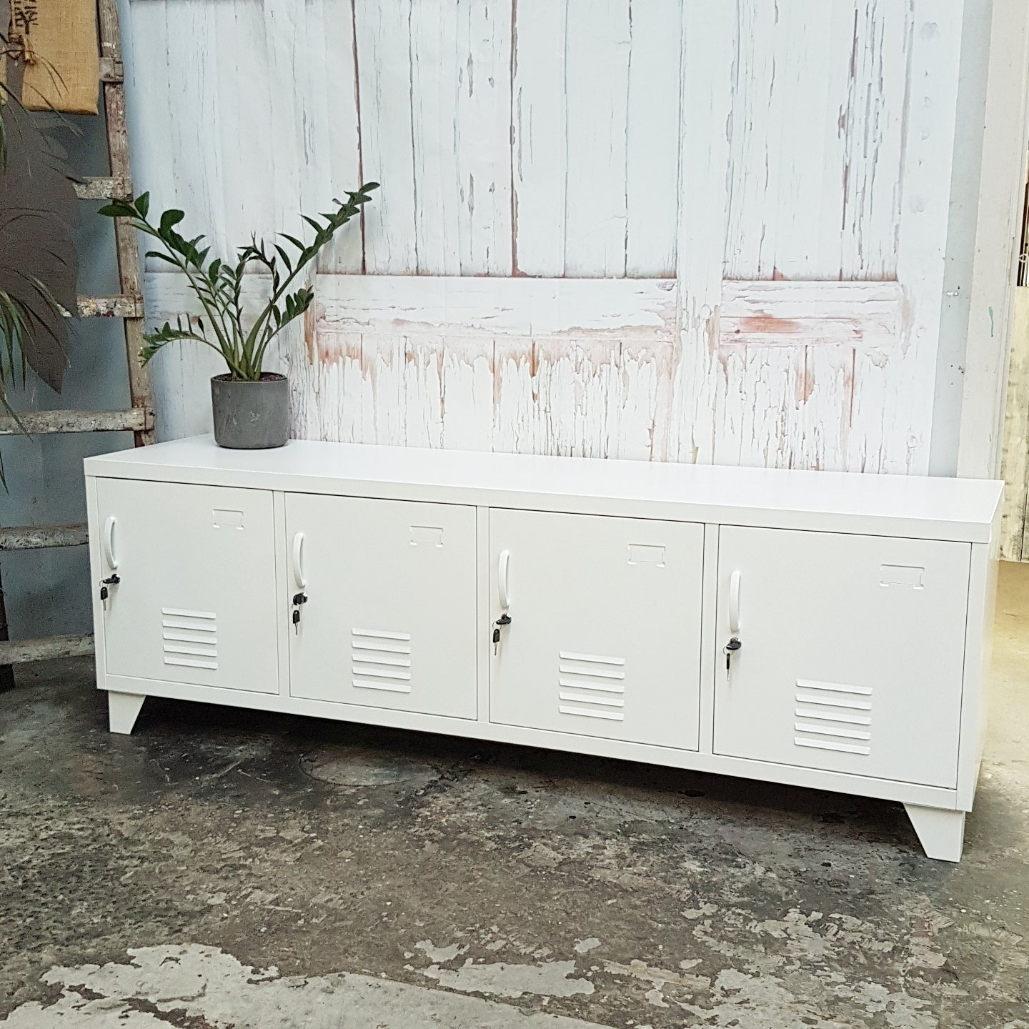 Large industrial White metal storage locker cabinet with plant against a rustic wooden wall