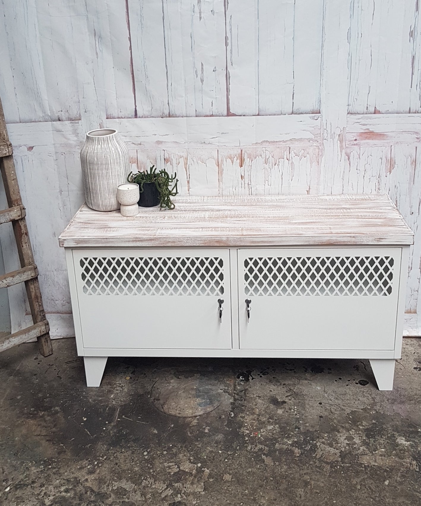 Small White metal TV cabinet with rustic white top in a rustic setting
