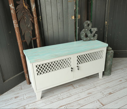 White metal TV cabinet with turquoise top in a rustic setting