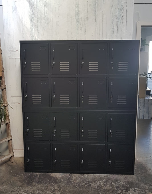 A large black metal 16-door staff locker unit with small rectangular doors and vent holes, standing upright on a floor.
